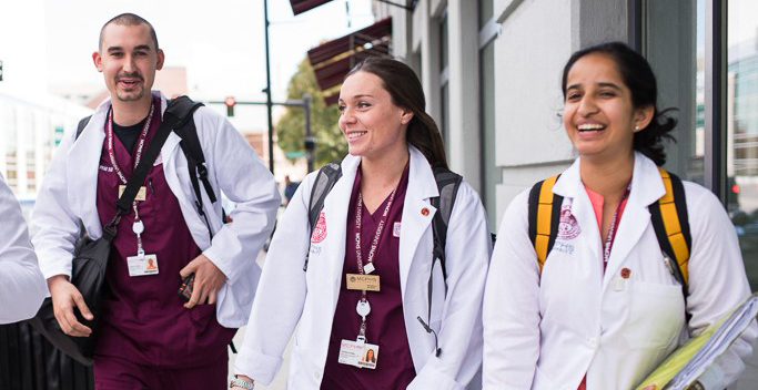Smiling students in scrubs walking down the street